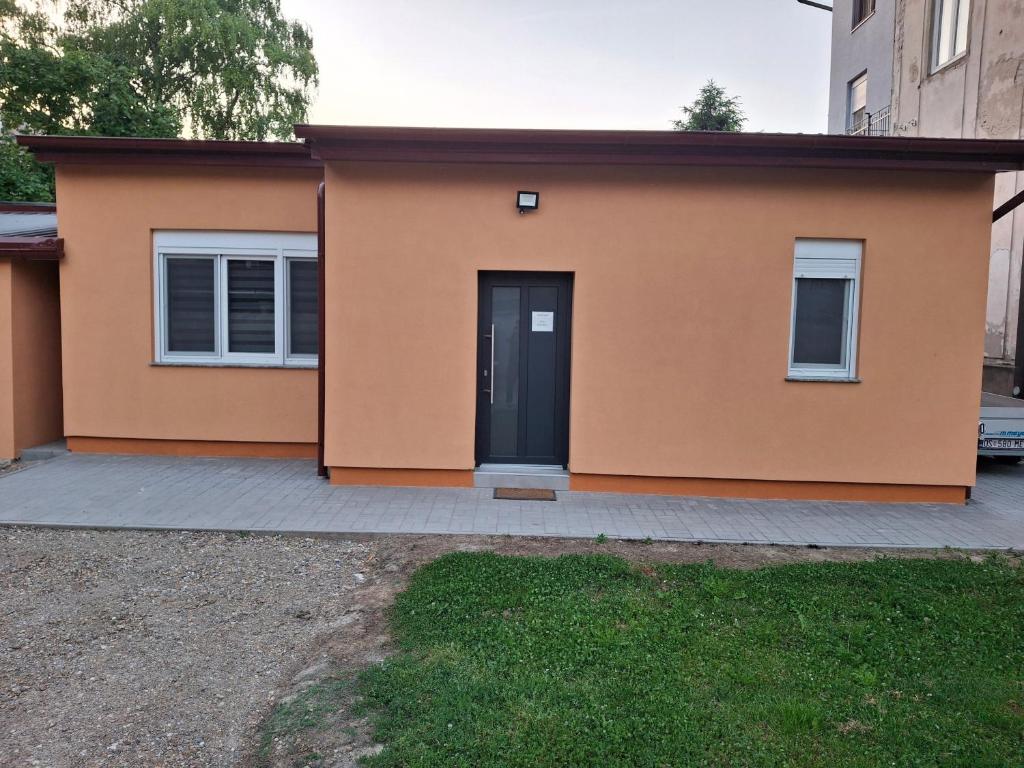 a house with a black door on a driveway at Apartman Kod Kestena in Osijek