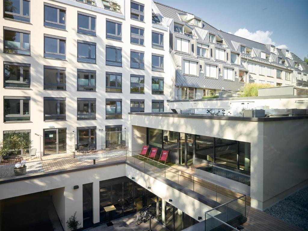 an apartment building with red chairs in front of it at Schwabinger Wahrheit by Geisel in Munich