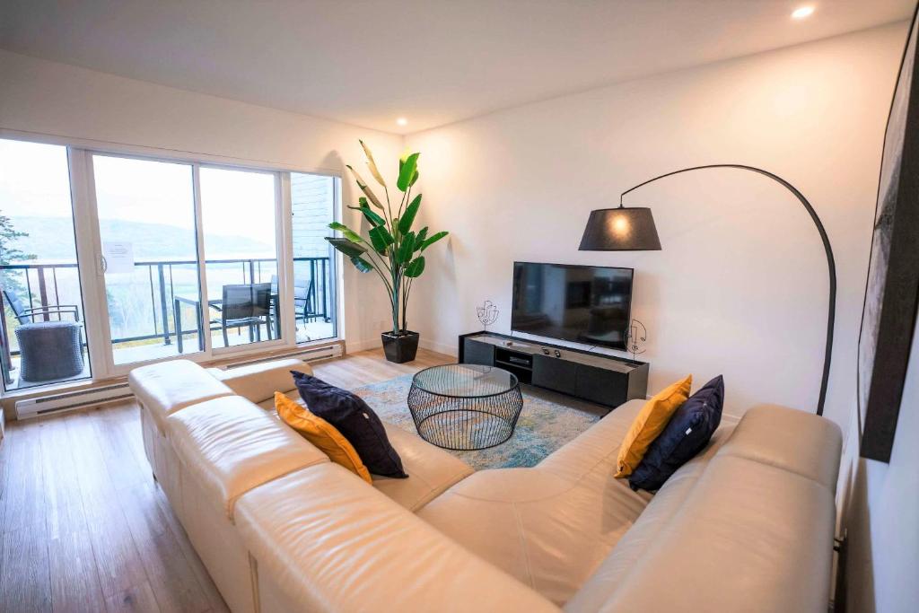 a living room with a couch and a television at 205 - Modern Suite - Pool and River View in Baie-Saint-Paul