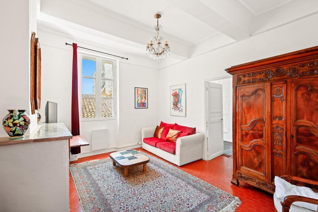 a living room with a red couch and a large wooden cabinet at Escapade elegante dans un ecrin d histoire in Hyères