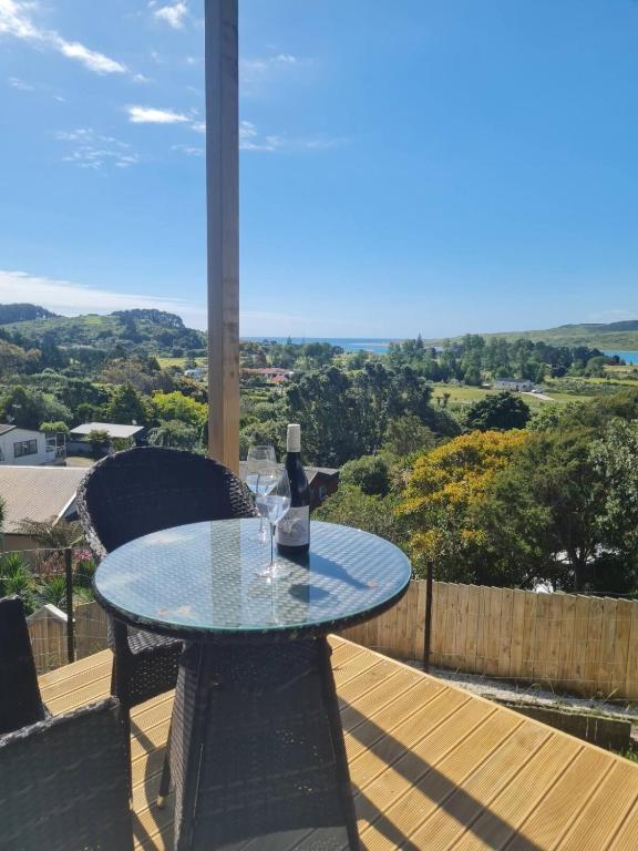 a glass table with a bottle of wine on a balcony at Rakaunui Retreat in Raglan