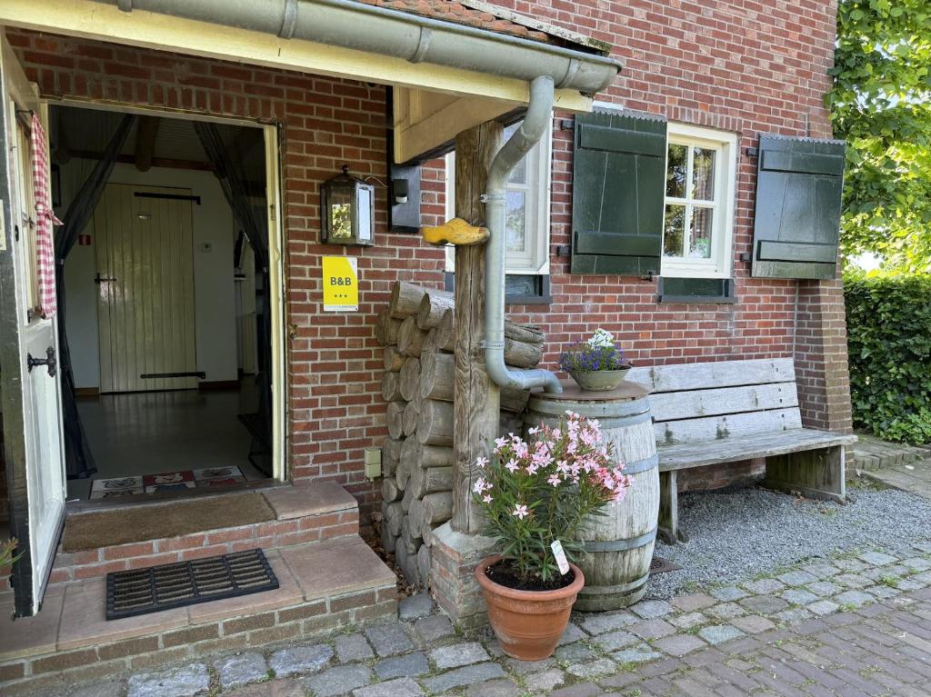 ein Backsteinhaus mit einer Bank und einem Gebäude in der Unterkunft B&B Maarle in Poppel