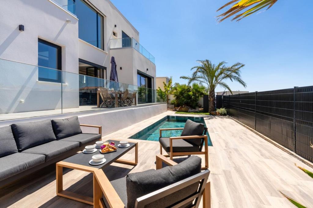 a patio with a couch and chairs next to a swimming pool at Villa Monégasque elegance & Exclusive seaside getaway in Sérignan