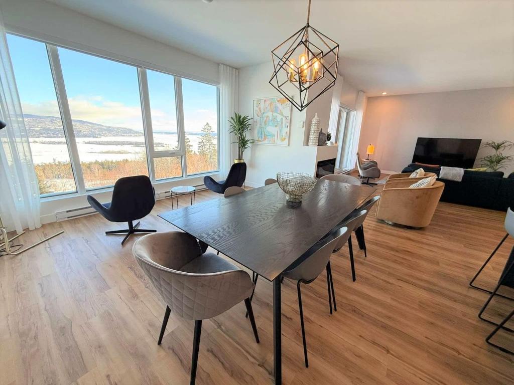 a living room with a dining table and chairs at 209 - Luxury Condo - Pool & River View in Baie-Saint-Paul