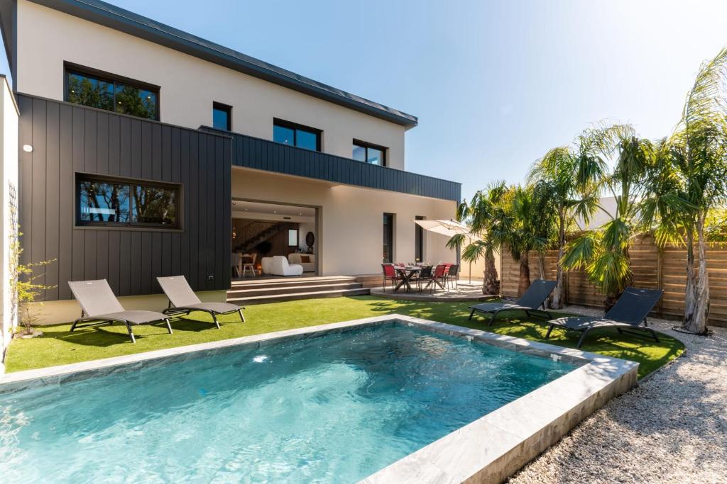 a swimming pool in front of a house at Villa Amphitrite Share beach & happiness in Le Grau-dʼAgde