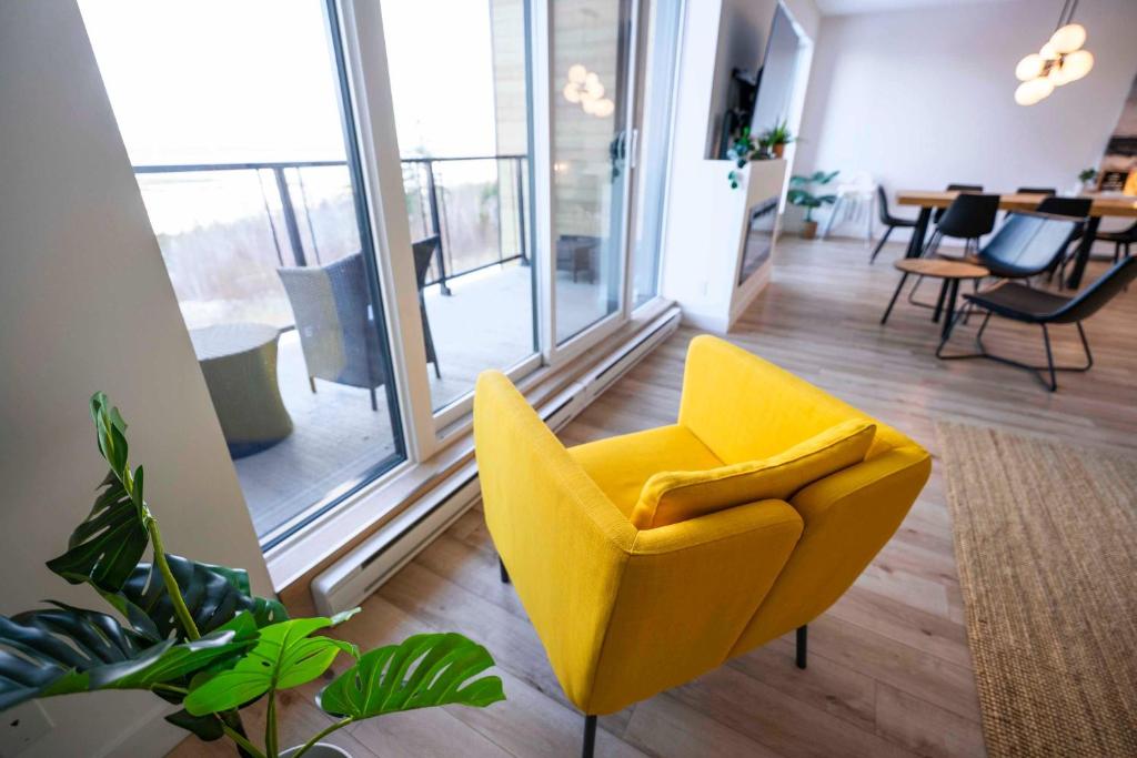 a yellow chair in the middle of a room at 210 - Chic Escape - View & Comfort with Pool in Baie-Saint-Paul
