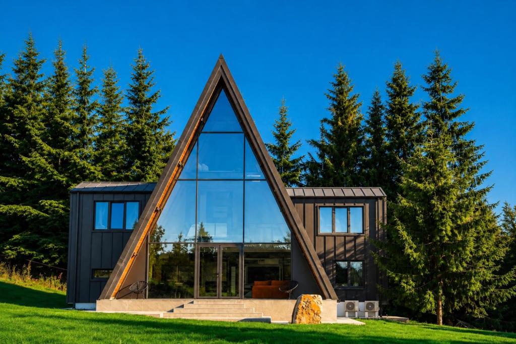 a house shaped like a triangle with glass at Tihuta Chalet in Piatra Fantanele
