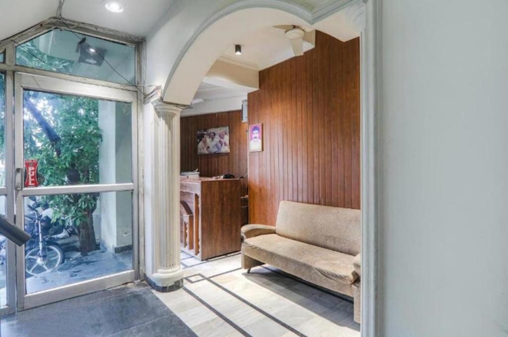 a living room with a couch and a glass door at Bless Inn in Prayagraj