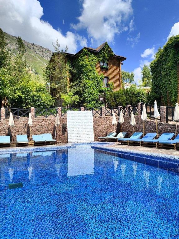 a large swimming pool with chairs and umbrellas at Nebesa Hotel EZ in Chimgan