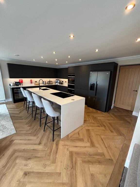 a kitchen with a white island with bar stools at Raasay Apartment in Fort William