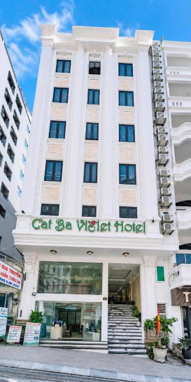 a white building with a cat be vida hotel at Cat Ba Violet Hotel and Apartment in Cat Ba