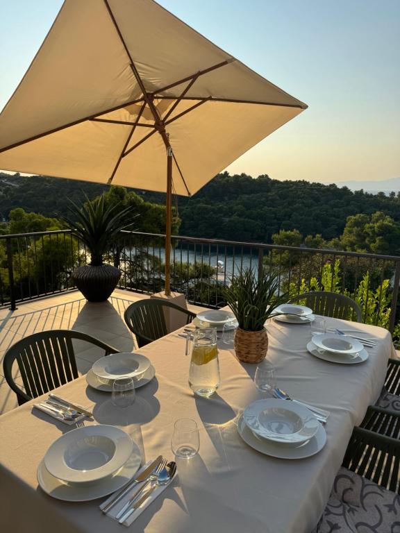 a table with plates and glasses and an umbrella at Villa Mila in Splitska