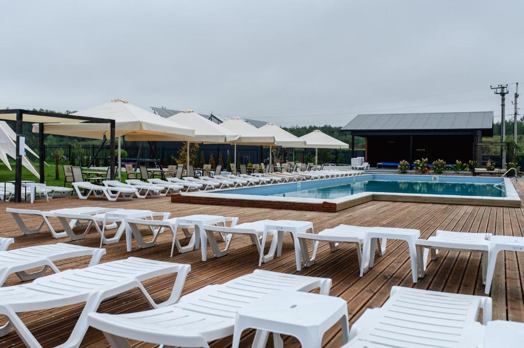 a row of white lounge chairs next to a pool at California Resort and SPA in Novoyavorivsk