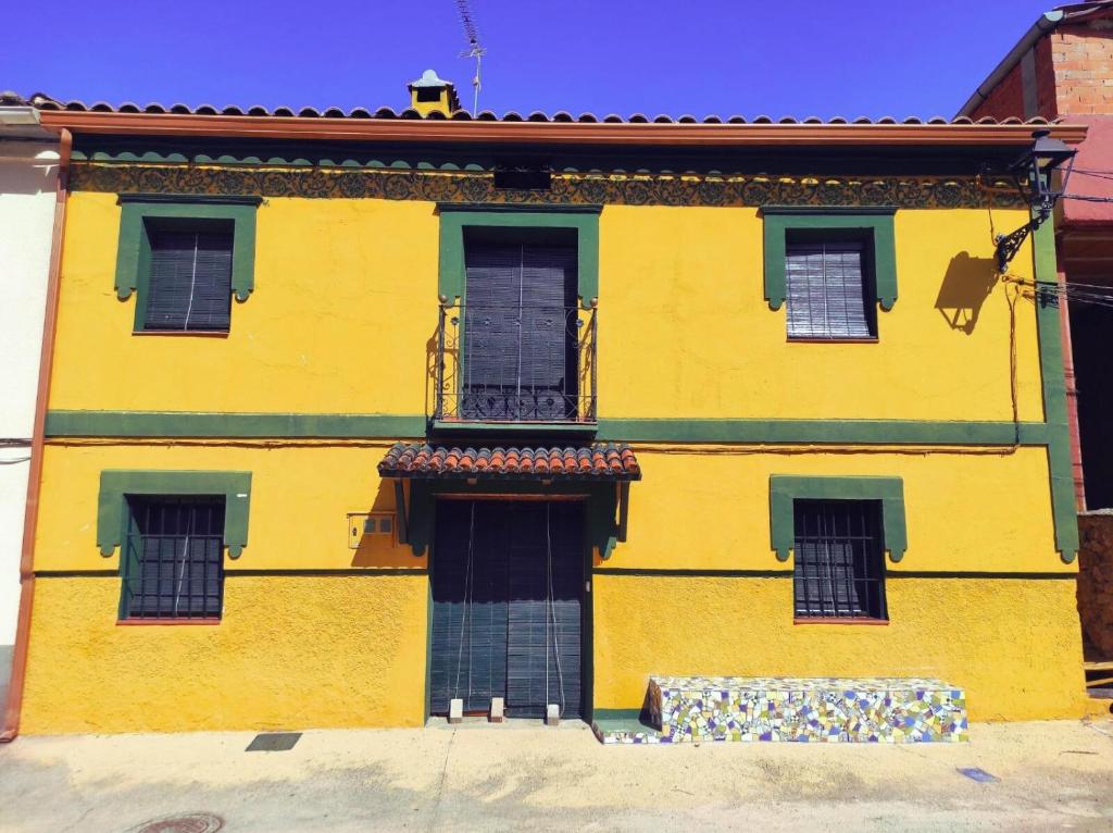 a yellow building with green windows and a balcony at La Salera - Casa Rural in Saelices de la Sal