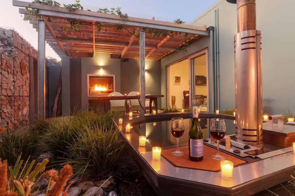 a patio with a table with wine glasses and a fireplace at 17 Marine - Apt 103 - Private Hot Tub & Garden in Hermanus
