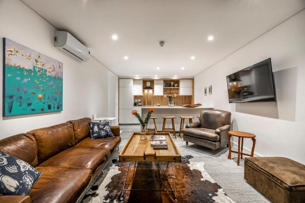 a living room with a brown leather couch and a table at 17 Marine - 2 Bedroom - Garden - Apt 104 in Hermanus