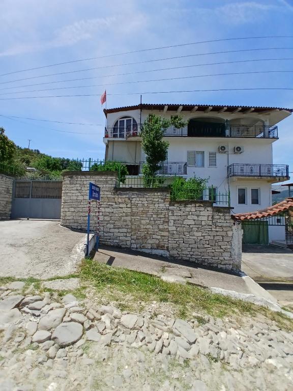 a building in front of a stone wall at Guest house Irvin in Berat