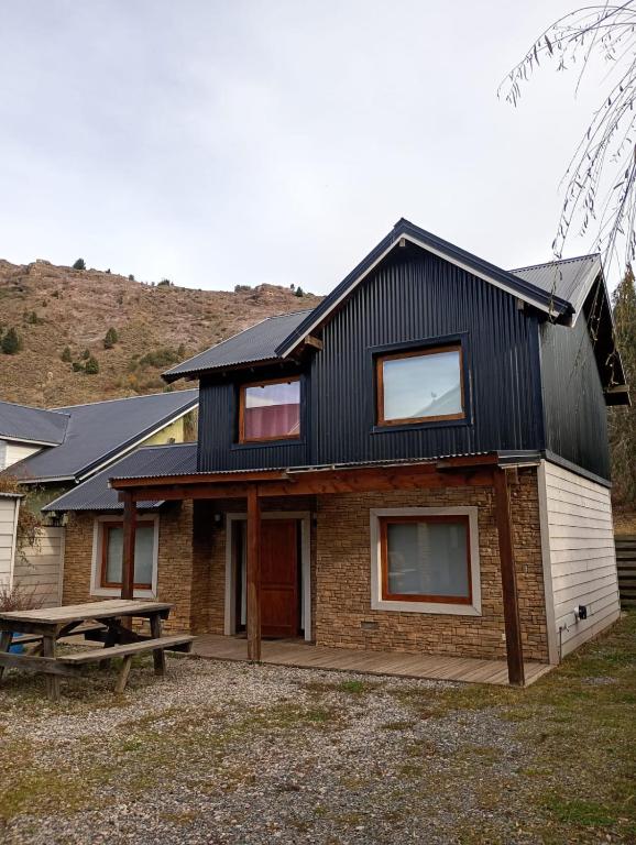 a house with a black roof and a picnic table at Casas Nahuilen in San Martín de los Andes