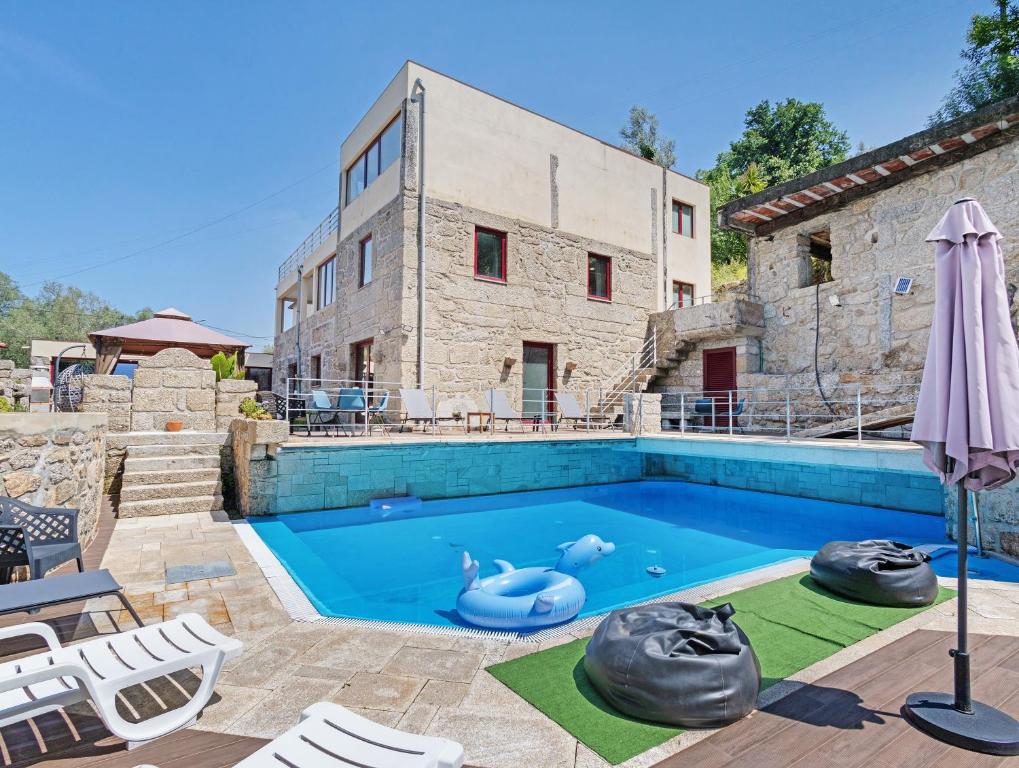 a swimming pool in front of a stone house at Quinta do Avô - Casa de Campo in Terras de Bouro