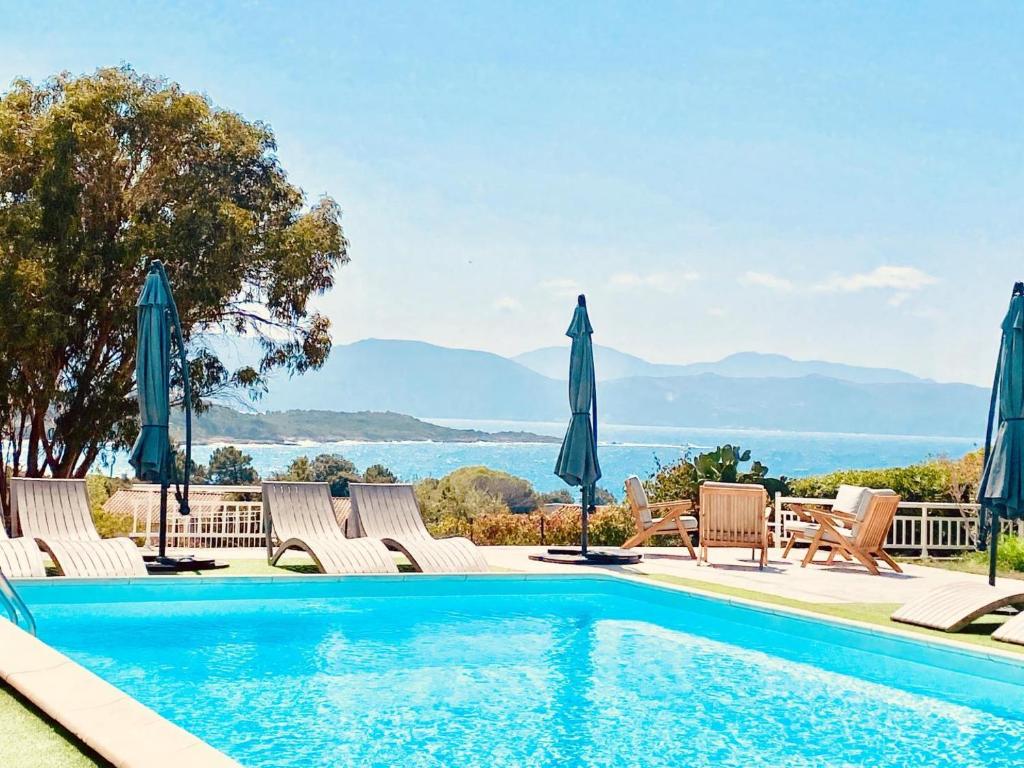 a swimming pool with chairs and umbrellas at Casa nova in Sagone