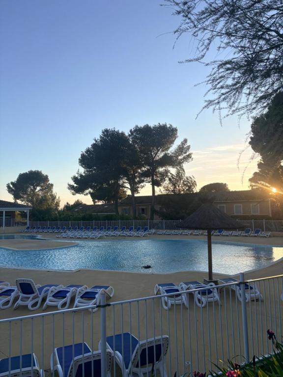 a pool with lounge chairs and an umbrella and a group ofitures at Maison avec jardin in Calvisson