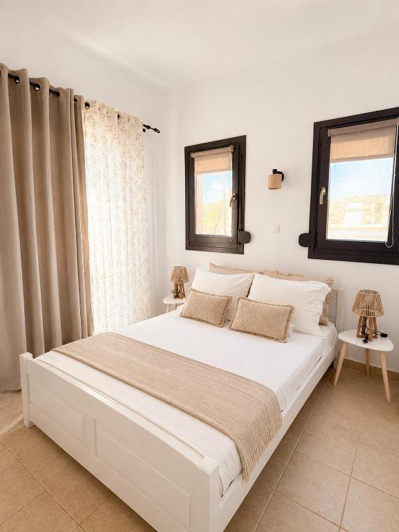 a bedroom with a large white bed with two windows at Pension Anastasia in Ammouliani