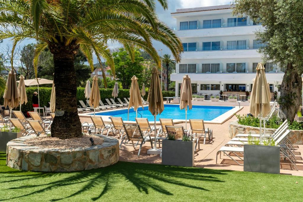 a hotel with a pool and chairs and umbrellas at THB Dos Playas - Adults Only in Cala Ratjada