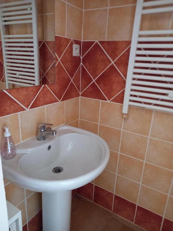 a bathroom with a white sink and brown tiles at La croce in Letia