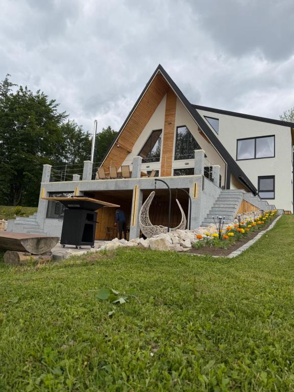 a house with a gambrel roof with a porch at A-frame Sofis House Valea Doftanei in Teşila