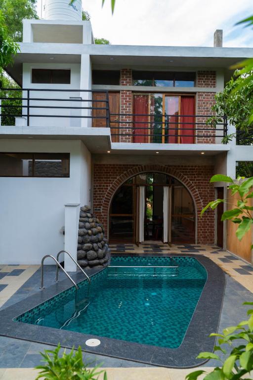 a house with a swimming pool in front of a house at Mango Orchards Two in Auroville