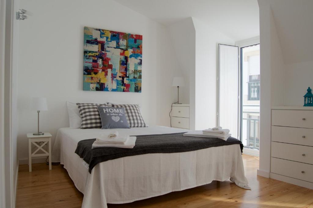 biała sypialnia z łóżkiem i obrazem na ścianie w obiekcie Casa do Chafariz w mieście Cascais