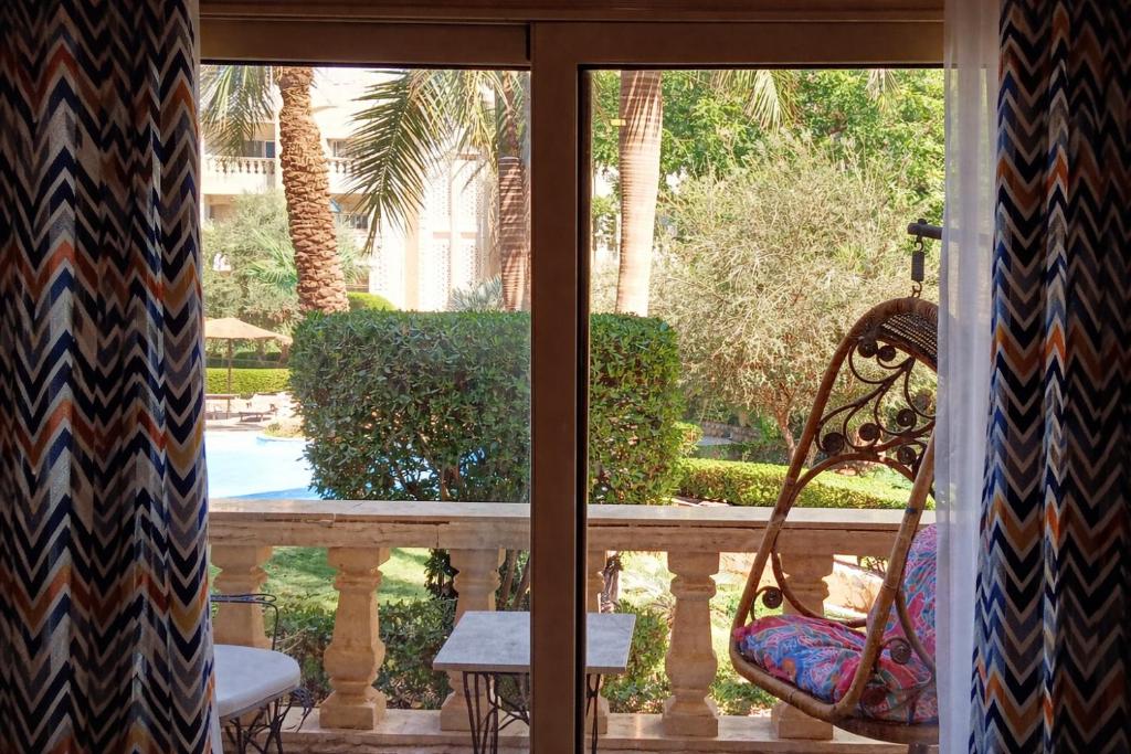 a view of a porch with a bench and palm trees at Casa Dòdò - Sunny Lakes Compound in Sharm El Sheikh