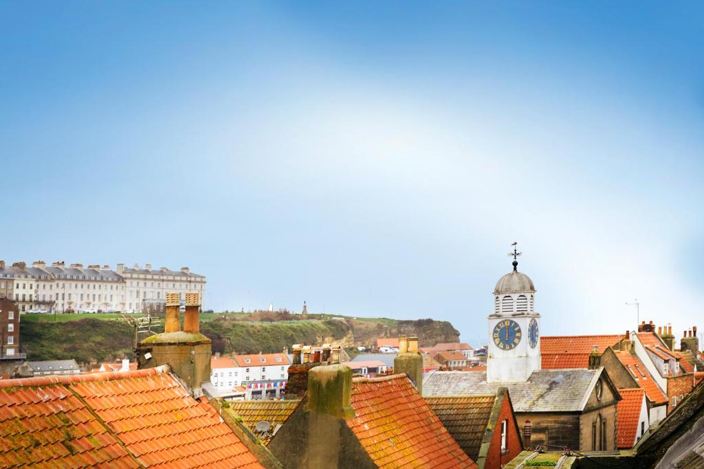 a view of a city with a clock tower and roofs at Whitby Old Town Stay, Sleeps 4, The Nest in Whitby