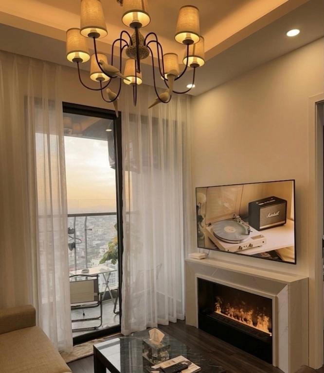 a living room with a fireplace and a chandelier at Anmie Home - Hoàng Huy CMC in An Khê