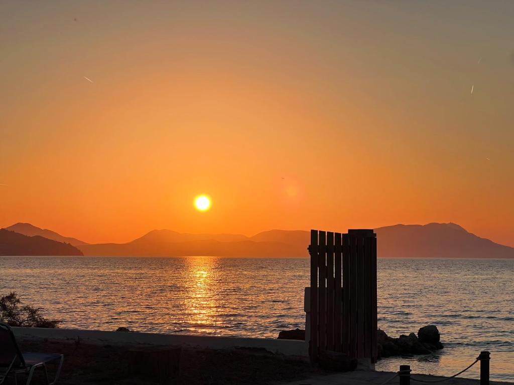 a sunset on the beach with the sun setting at Dimitra Houses 1 - Seaside in Lefkimmi