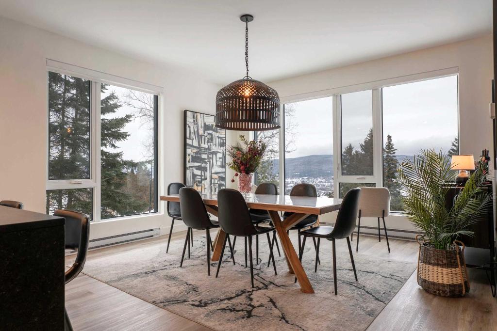 a dining room with a table and chairs and windows at 211 - Bright Condo - Pool and Cozy Atmosphere in Baie-Saint-Paul