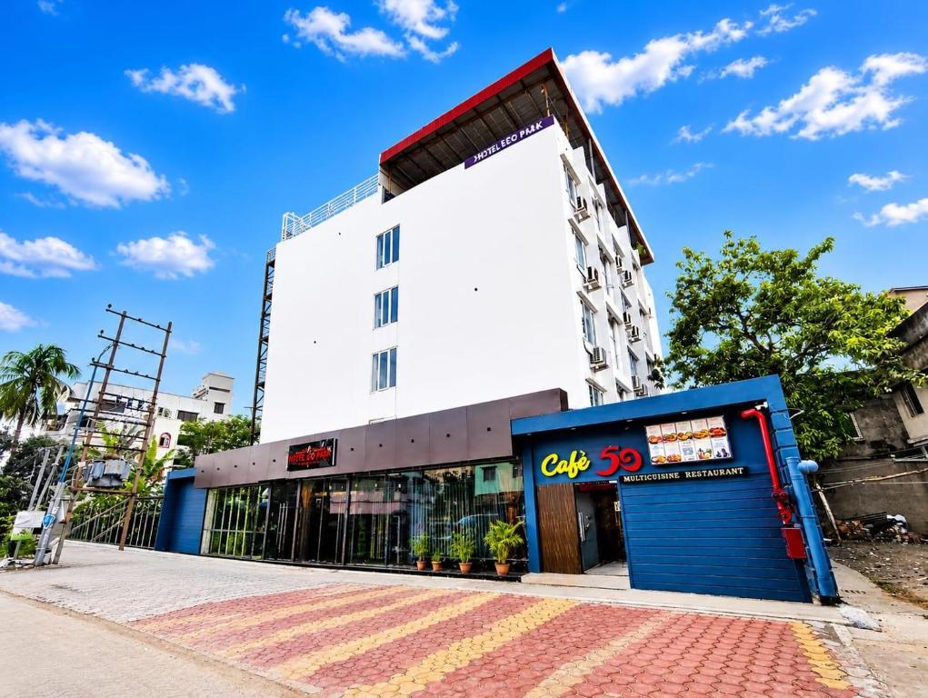 a tall white building with a blue storefront at Hotel Eco Park By Carlton Suites in kolkata