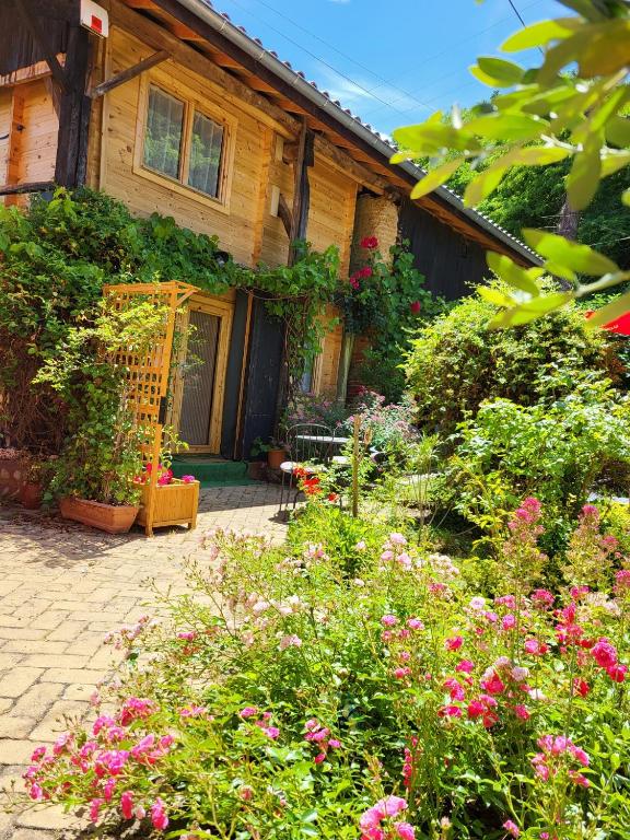 a garden in front of a house with flowers at Le chalet caché, au pied des Chambarans in Saint-Siméon-de-Bressieux