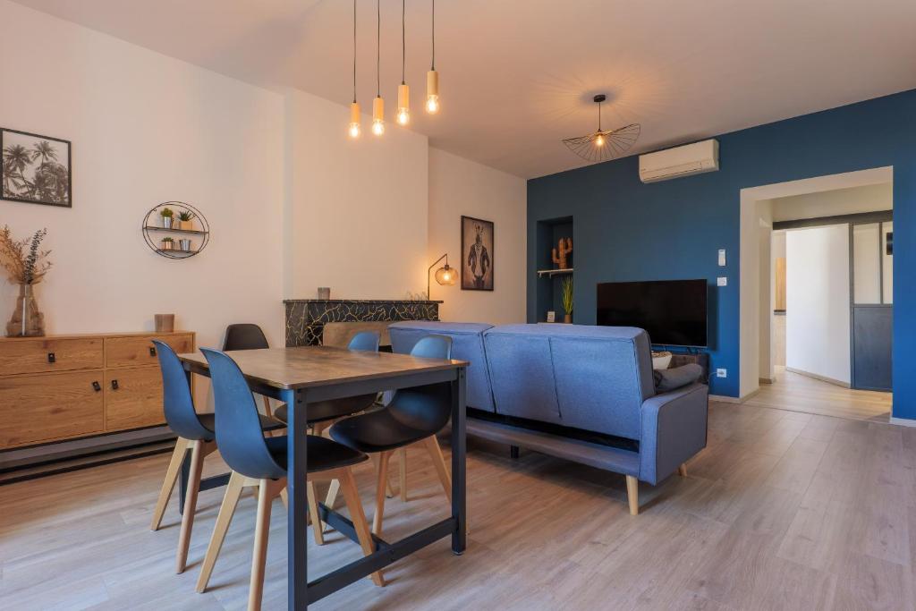 a living room with a dining table and blue chairs at T4 Cosy - Château - Wifi in Aubenas