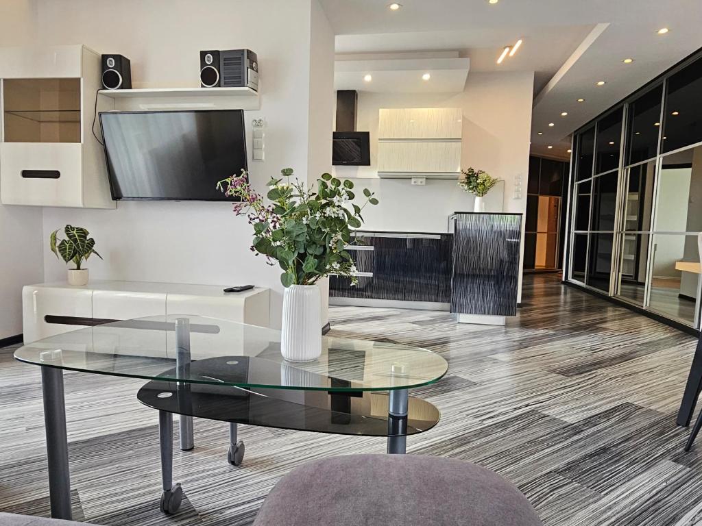 a living room with a glass table and a kitchen at Apartament SPACE & SUN z wewnętrzym ogrodzonym parkingiem in Toruń