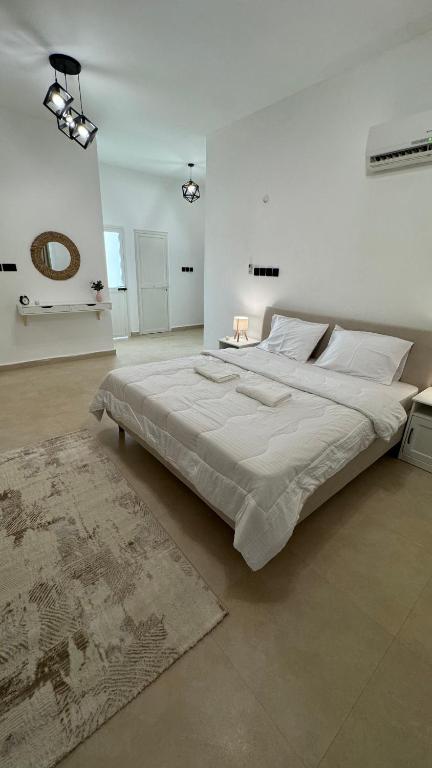a white bedroom with a large bed and a rug at The Inn Salalah in Salalah