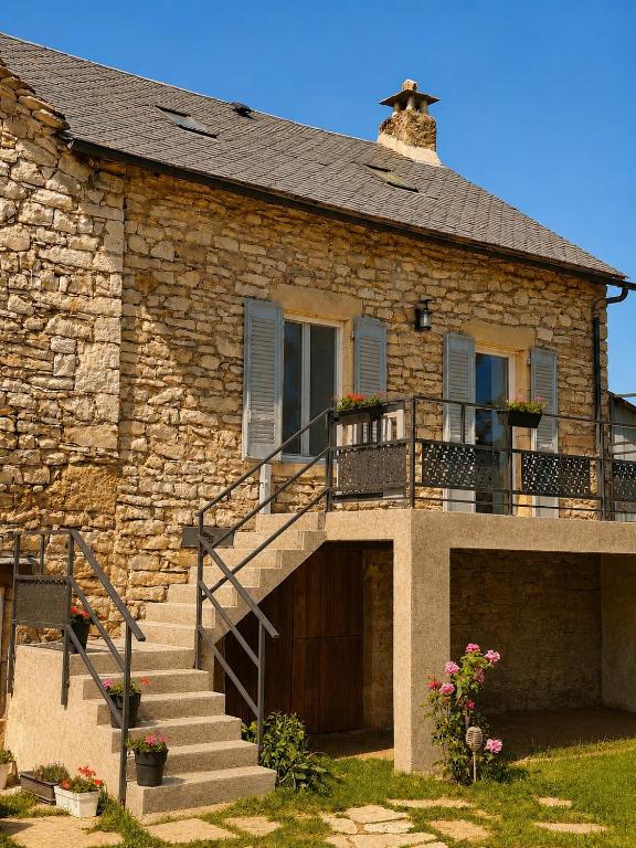 a stone house with stairs and a balcony at Gîte Caussenard rénové in Le Massegros