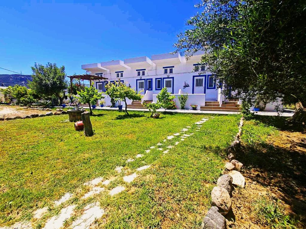 a large white house with a yard in front of it at Nefeli Apartments in Kefalos