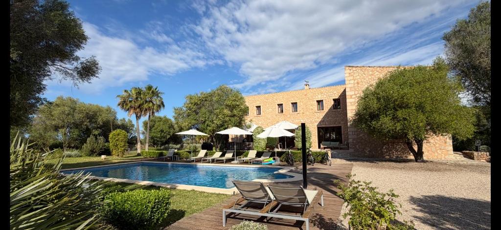 a pool with chairs and umbrellas next to a building at Finca Latenéa in Islas Baleares