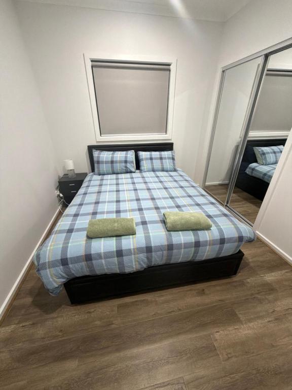 a bedroom with a bed with two pillows and mirrors at Private Room in Rockbank in Rockbank