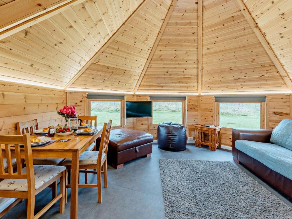 a room with a wooden ceiling with a table and a couch at 1 Bed in Lanark oc-91252 in Libberton