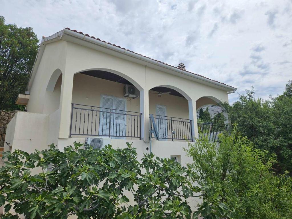 a white house with a balcony and trees at Jelena Holiday House in Karlobag