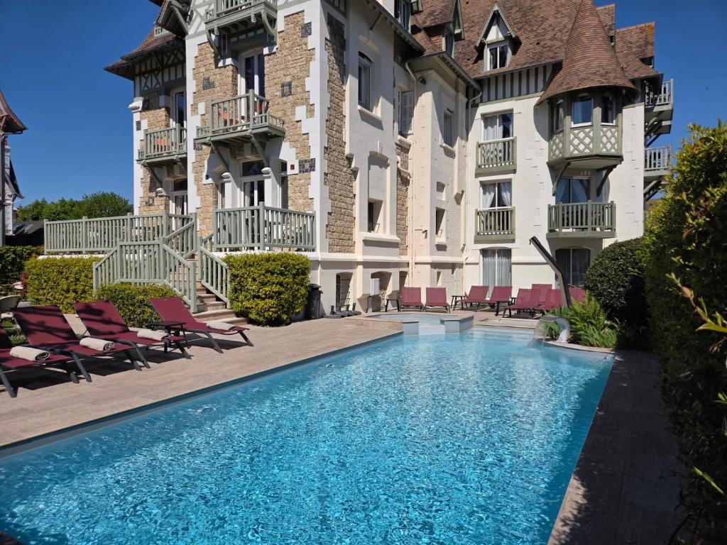 a swimming pool in front of a building at Villa Augeval Hôtel de charme & Spa in Deauville
