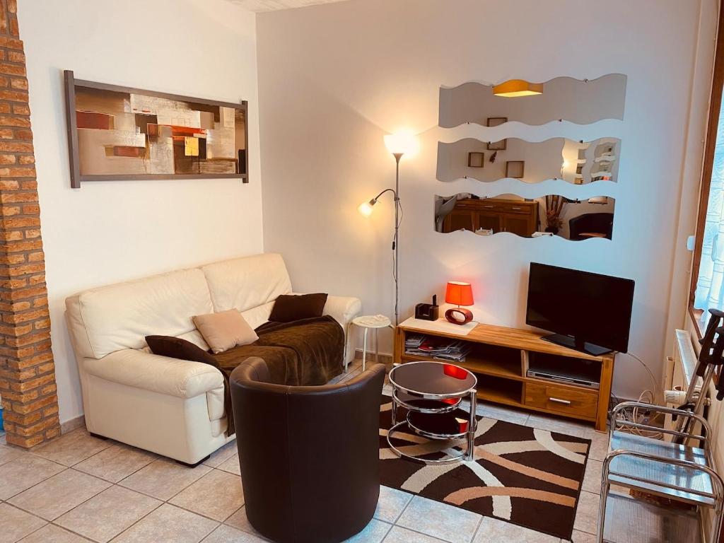 a living room with a couch and a tv at Les Volets Blancs in Étaples