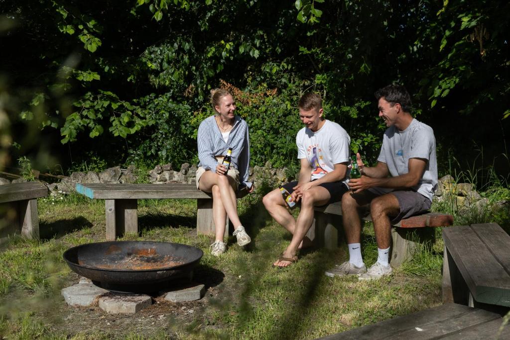 three people sitting on a bench next to a grill at Yart in Scharendijke